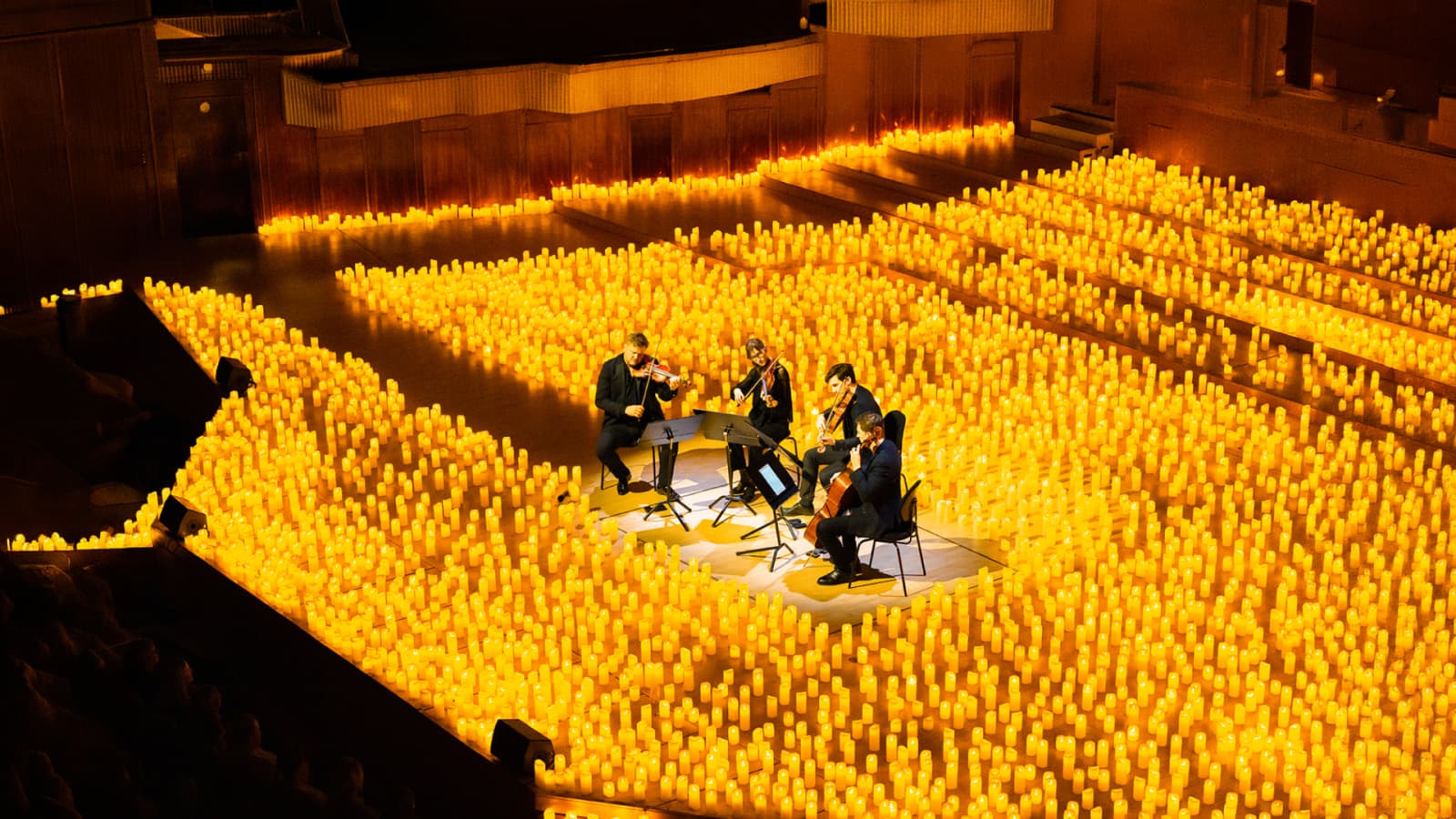A string quartet plays surrounded by hundreds of candles