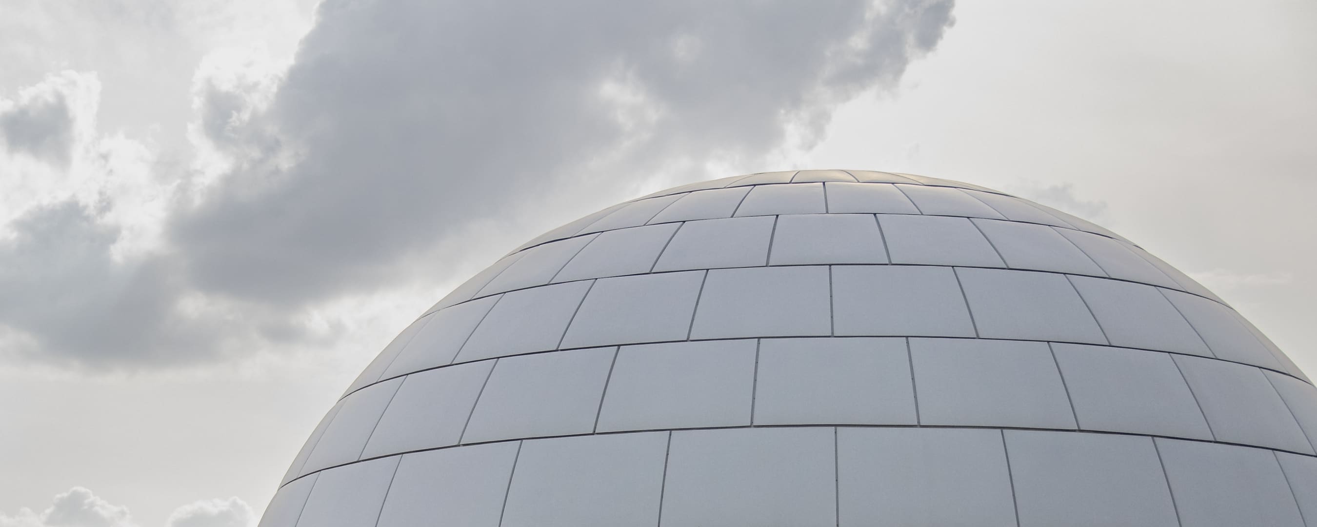 La cúpula blanca de azulejos del Planetario de Madrid bajo un cielo nublado