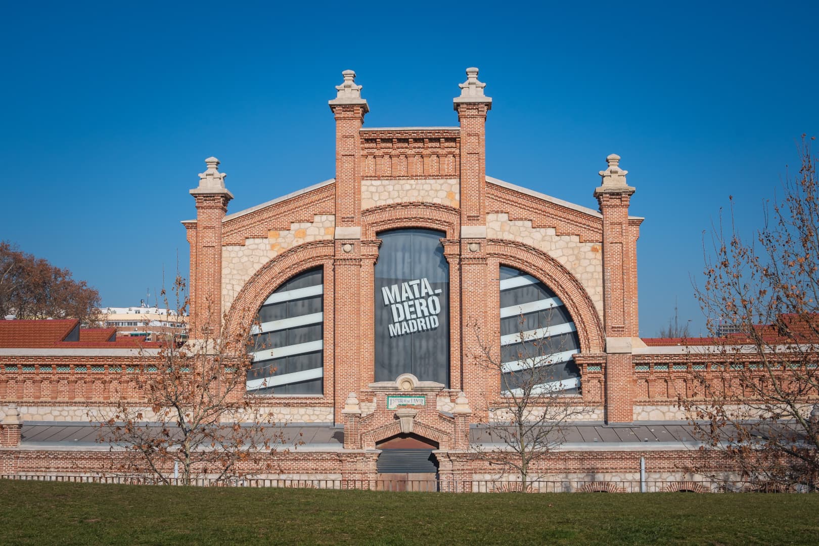 La fachada de ladrillo y azulejo de Matadero Madrid bajo un cielo azul despejado