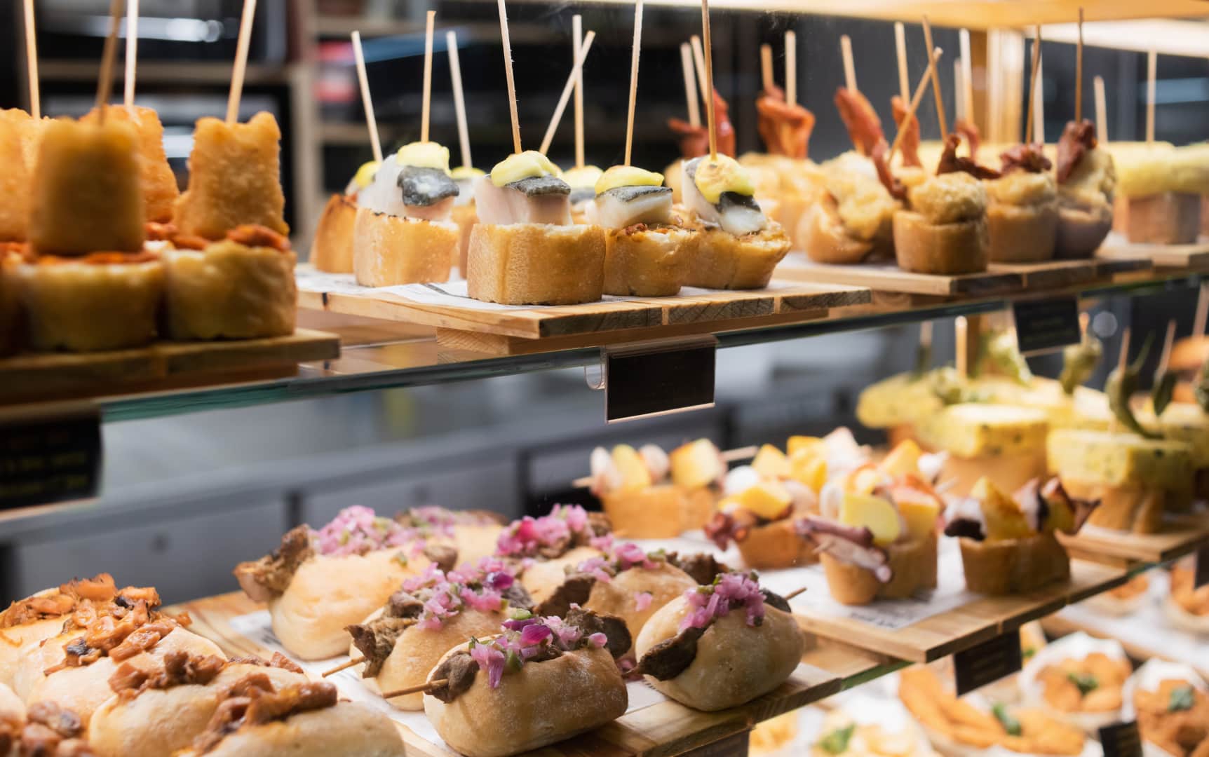 Pintxos and tapas lined up in a bar display case