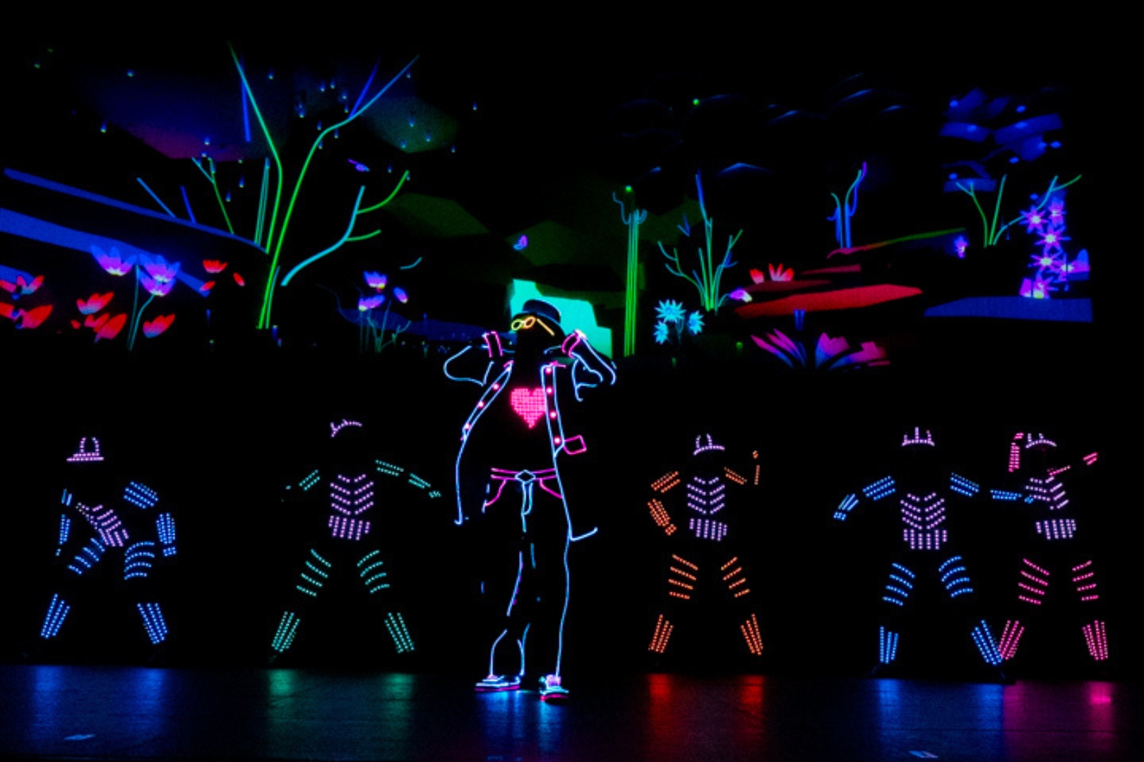 Groupe de 6 danseurs avec des costumes lumineux sur scène